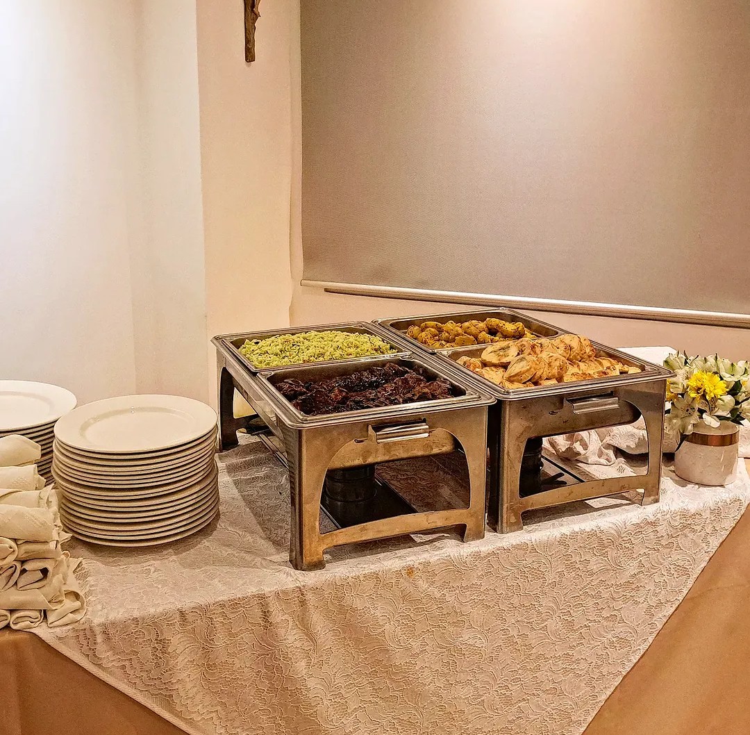 Buffet caliente con chafing dishes y vajilla lista para servir