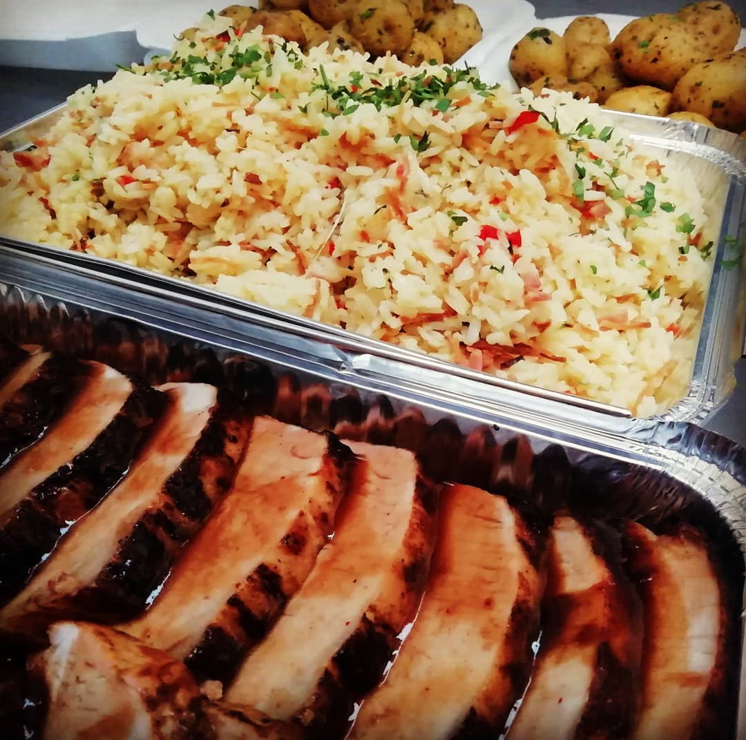 Buffet con bandejas de carne asada, arroz y papas